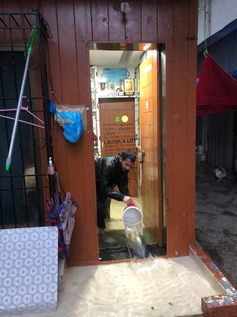 Hockey star Yuvraj Walmiki using a bucket to remove water that entered his house